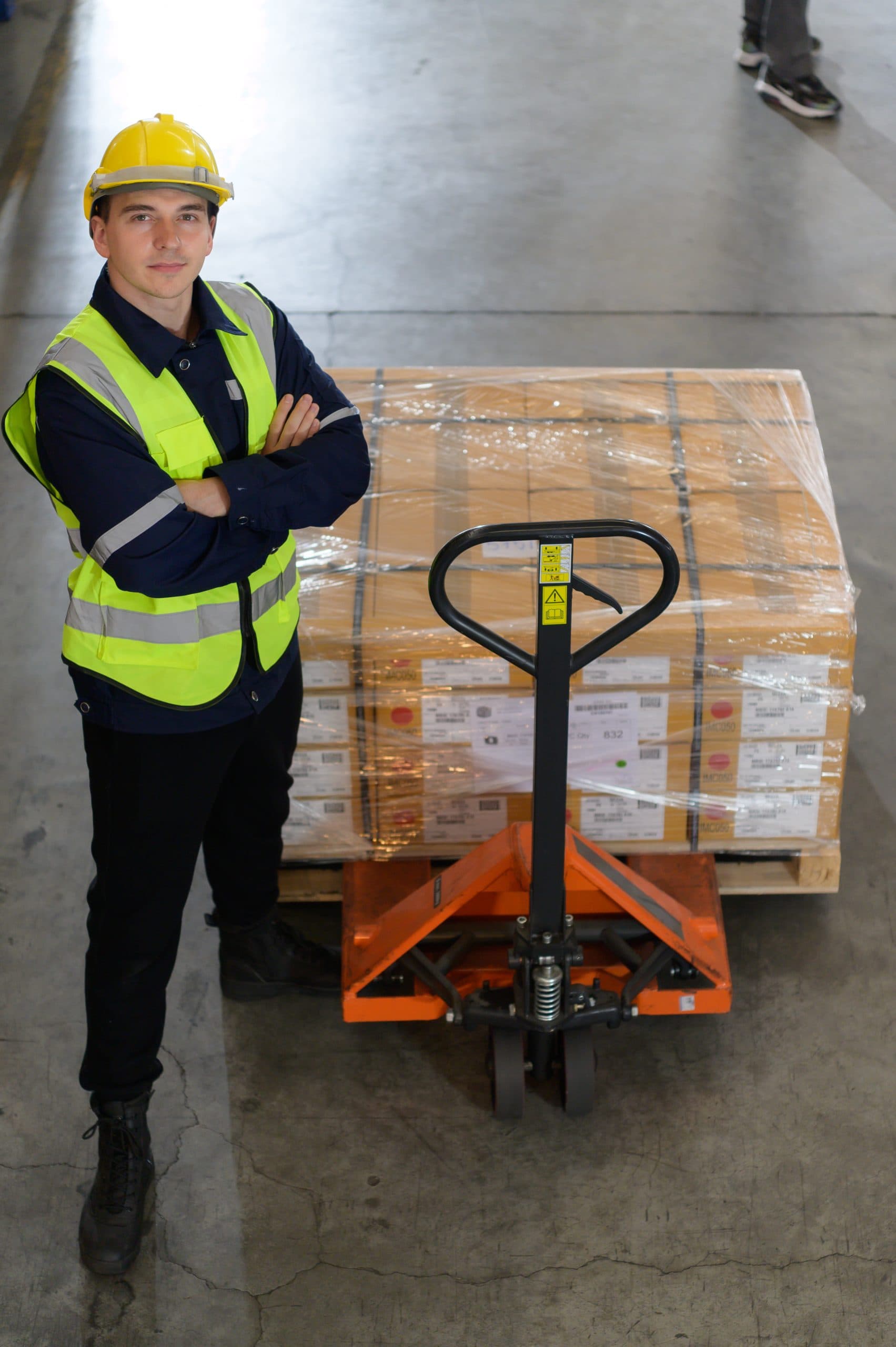 Worker in auto parts warehouse use a handcart to work to bring the box of auto parts into the storage shelf of the warehouse waiting for delivery to the car assembly line